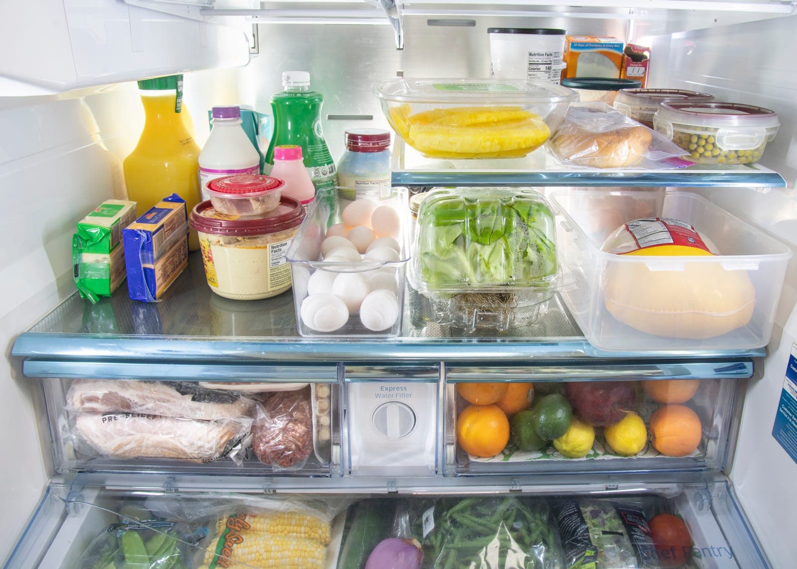 The open shelves and drawers of a fully stocked refrigerator, from eggs to produce