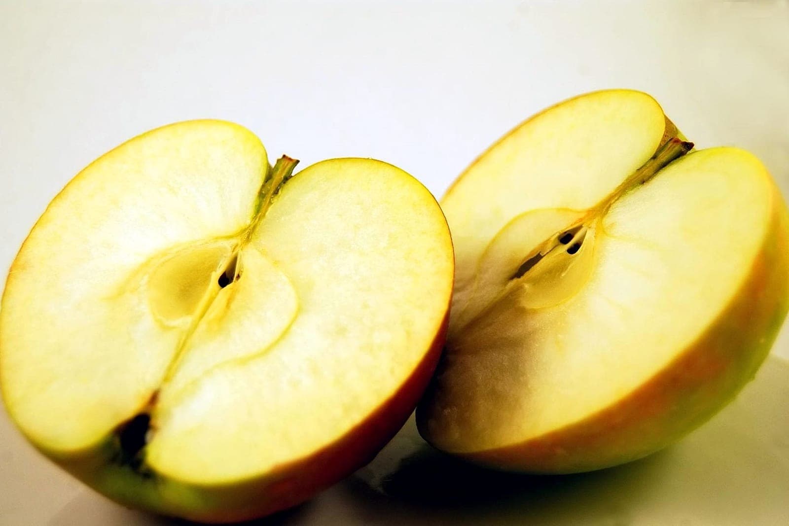 Two halves of a freshly cut apple showing pale yellow flesh
