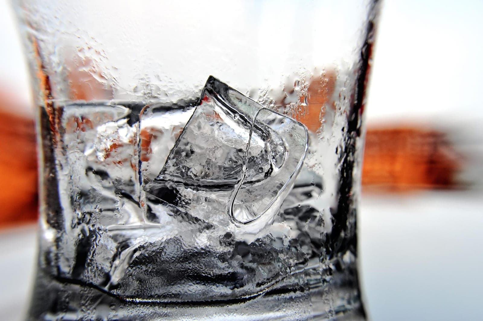 A single clear ice cube melting inside a glass, free of the white cloudy core typical of tray ice