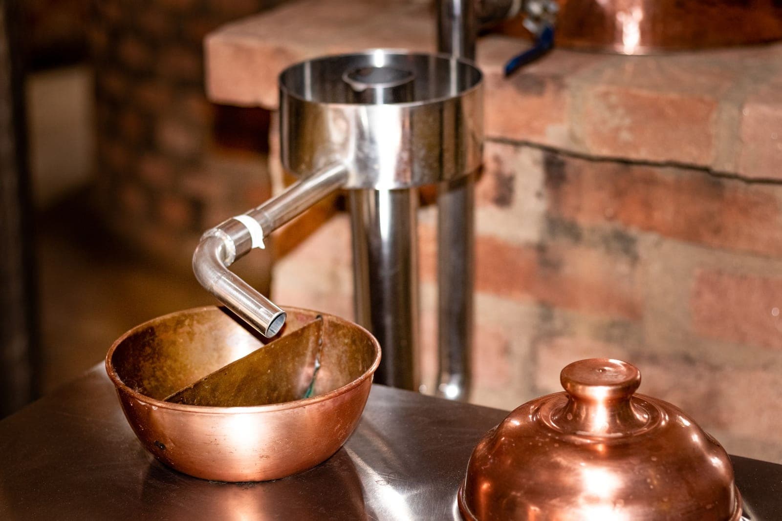 A copper spirit bowl catching the run from a still's condenser pipe