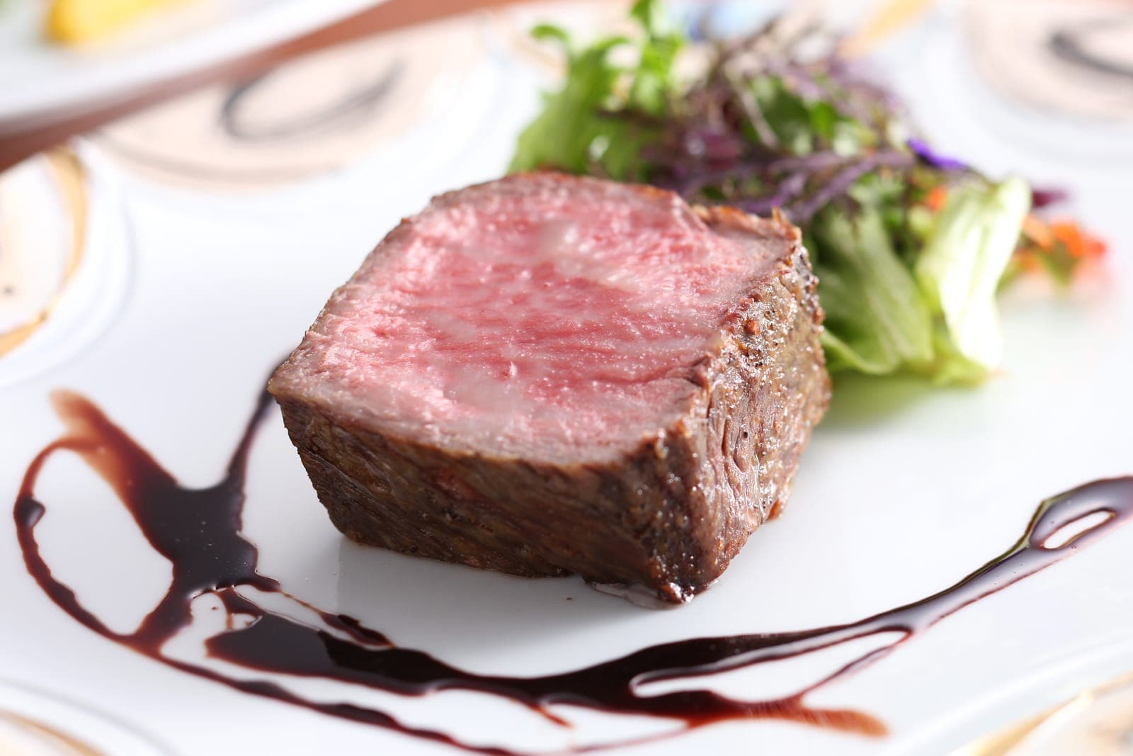A plated cross-section of dry-aged beef, deeply browned at the crust and rosy at the center