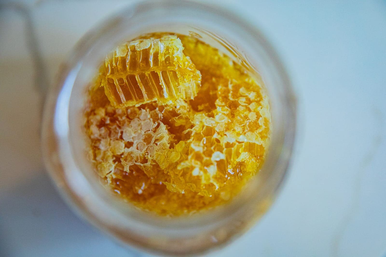 A jar of honey with pieces of honeycomb suspended in it, seen from above