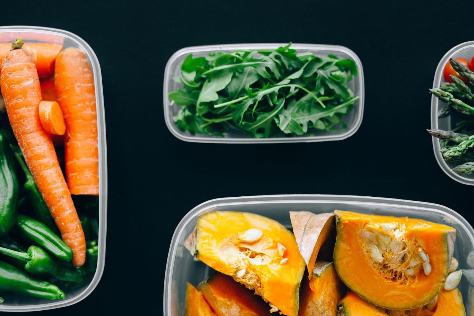 Carrots, rocket, peppers and squash packed into clear storage containers