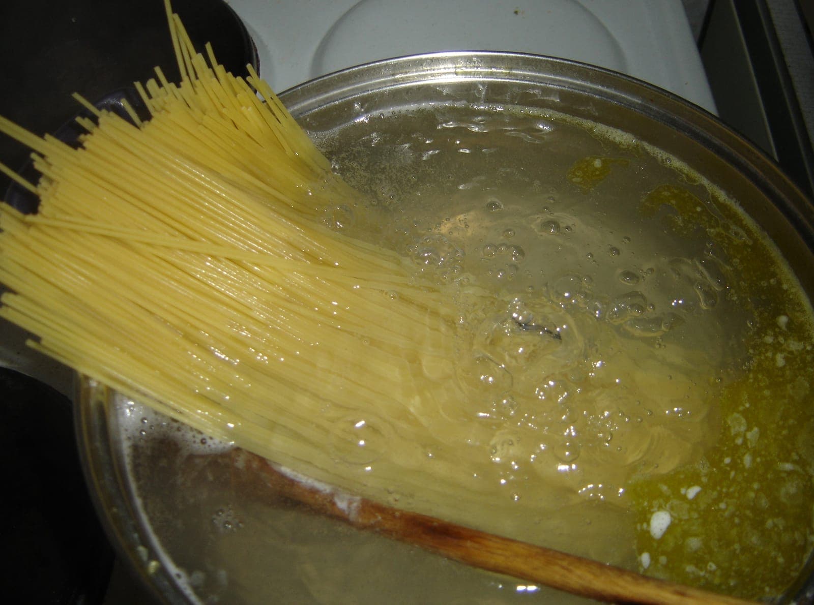A bundle of dry spaghetti going into a pot of boiling water